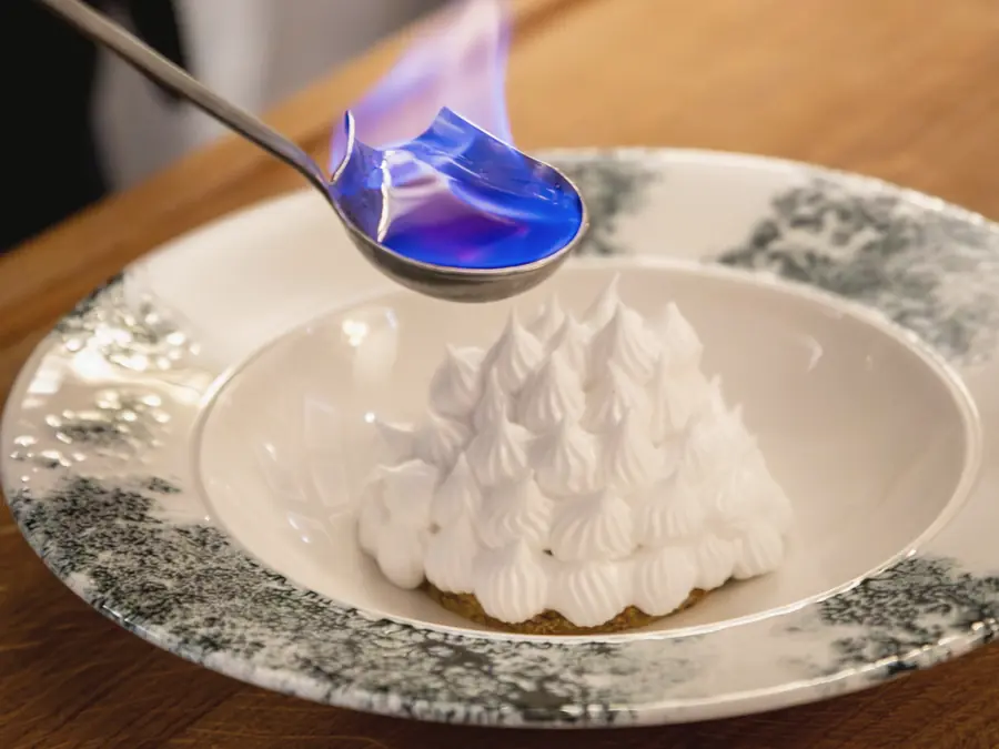 A baked Alaska being flamed with a spoon of lit spirit