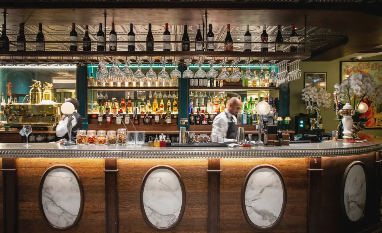 The bar at Sage: marble ovals set into a wooden counter, shelves of bottles behind