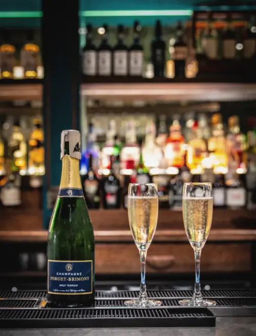 A bottle of Champagne and two flutes on the bar