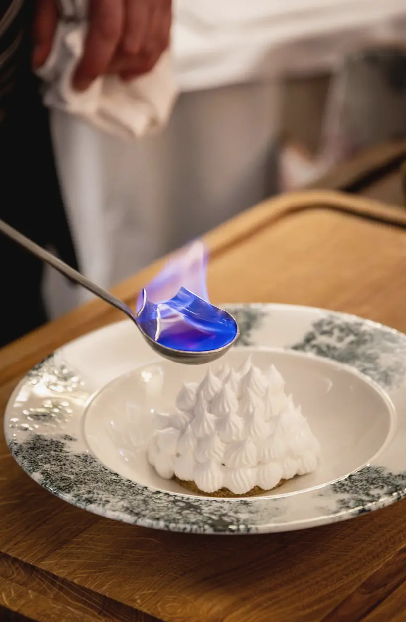 A spoon of flaming spirit held over a baked Alaska